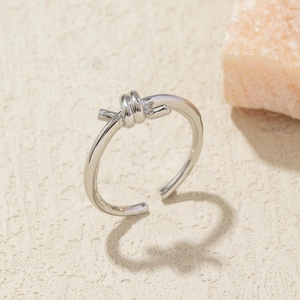 Detailed close-up of a silver knot ring with polished finish on a stone surface