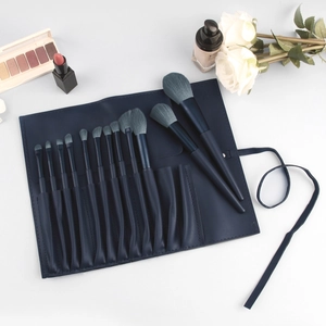 Detail view of 13 blue makeup brushes with a PU leather roll case on white background
