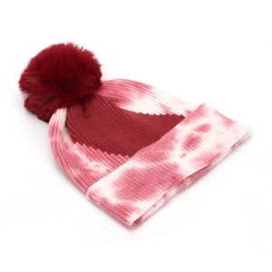Detailed view of tie-dye knit beanie with red and white gradient and fluffy pom-pom