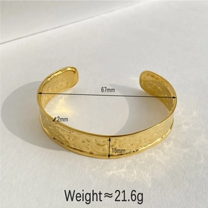 Detailed macro view showing the irregular hammered texture and dimensions of the gold bangle