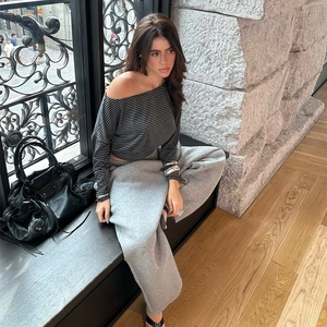 Detail of off-shoulder striped long sleeve top and grey joggers on a female model