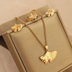 Golden ginkgo leaf necklace ring and earrings set displayed on a beige jewelry box