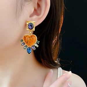 Close-up of vintage baroque gold earrings with heart-shaped colorful rhinestones