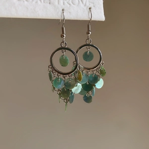 Detailed view of bohemian silver fish-scale earrings with turquoise shell tassel fringe