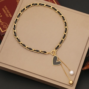 Detail of vintage heart pendant necklace with leather chain and dangling pearl