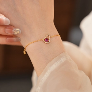 Detailansicht des 18K vergoldeten Armbands mit rotem Edelstein und Zirkon am Handgelenk