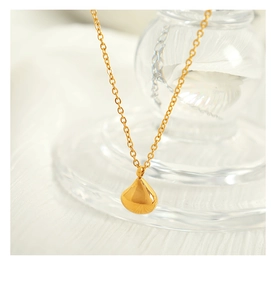 Macro shot of minimalist gold teardrop pendant on a fine metal chain for women
