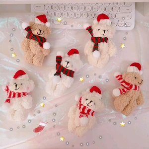 Close-up of plush teddy bear charms with Christmas hats and scarves in beige and white