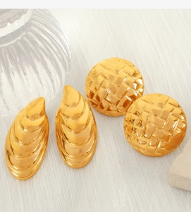 Detailed macro view of gold embossed shell earrings with woven texture on fabric
