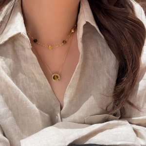 Gros plan du collier plaqué or 18k avec pierre œil de tigre et détails en cristal