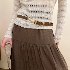 Close-up of slim brown leather belt with gold buckle on model waist over beige knitwear