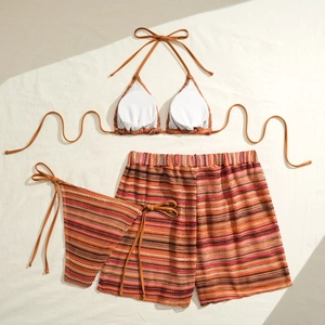 Detailed flat lay of three-piece striped bikini set with knitted texture on cream fabric