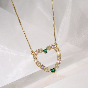 Gros plan du pendentif cœur doré avec des pierres zircones colorées et chaîne maille