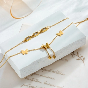 Detail of gold-plated butterfly anklet with crystals and tassels on a stone base