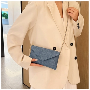 Blue envelope chain bag with vintage denim texture worn over a white blazer