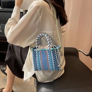 Colorful woven bucket bag with blue drawstring liner and light green shoulder strap