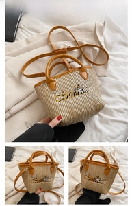Detail of orange woven straw bucket bag featuring tiger embroidery and leather handles
