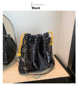 Detail of black sequined bucket bag with yellow rope drawstring and gold chain strap