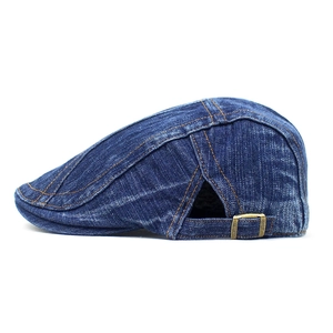 Close-up of vintage blue denim beret showing washed cotton fabric and metal side buckle