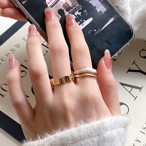 Detail of gold textured and wave pattern stacking rings with white enamel on hand