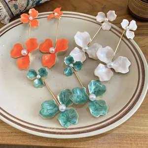 Elegant floral drop earrings with white pearls in orange, cream white, and teal colors