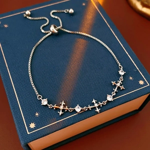 Silver bracelet detail showing zircon stones, cross charms, and adjustable slider clasp