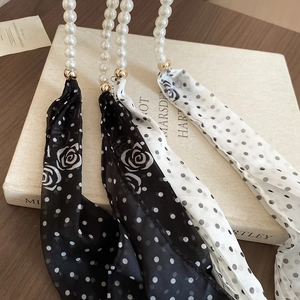 Detail of elegant pearl strap featuring floral polka dot silk ribbons and gold hardware