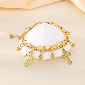 Detail of gold double-layer chain bracelet with cross pendants on beige silk