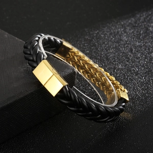 Close-up of black braided leather bracelet with golden magnetic clasp on a black gift box