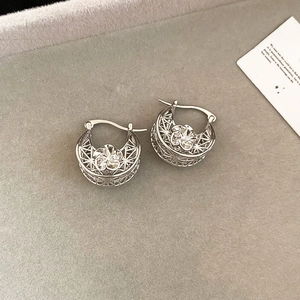 Macro view of silver hollow flower drop earrings on a grey velvet jewelry display tray