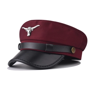 Detail of burgundy military cap with black leather visor and silver bull metal emblem