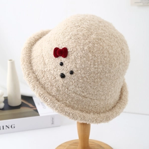 Detailed texture of beige faux shearling fisherman hat with red bow and bear embroidery