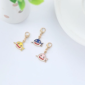 Close-up of colorful cartoon shark metal keychains in yellow, blue and pink enamel