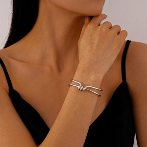 Detail of silver double-layered knot open cuff bracelet on a female wrist