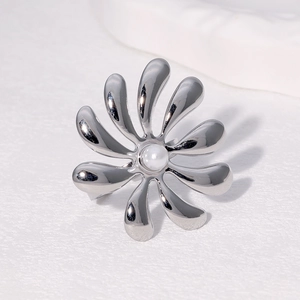 Silver flower-shaped stainless steel ring with a central white pearl on white surface