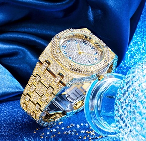 Detail of gold iced-out watch with Arabic numeral dial on blue silk background
