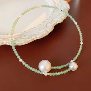 Detailed macro view of white pearls and green beads with silver spacers on a luxury necklace