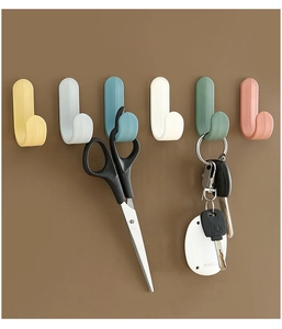 Close-up of colorful J-shaped wall hooks holding keys and scissors on a brown wall