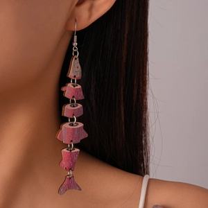 Close-up of articulated fish-shaped wooden earring with purple pattern and metal hooks