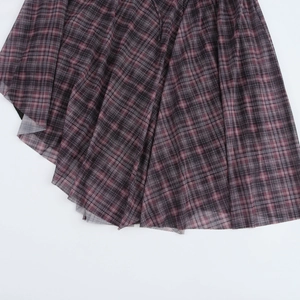 Detail of dark plaid pleated dress with lightweight sheer fabric and uneven hemline
