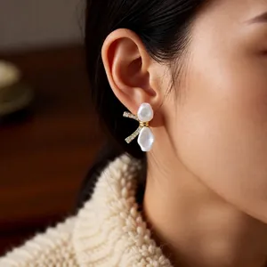 18k gold plated bow earrings with white drop pearls and cubic zirconia on model