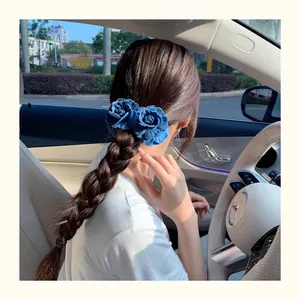 Detail of blue denim rose hair clip worn on a braided hairstyle in a luxury car setting