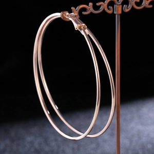 Detailed view of polished rose gold large hoop earrings on a black display stand