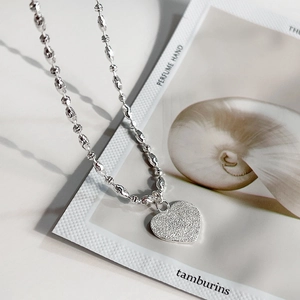 Macro detail of textured heart pendant and unique bead chain in 925 sterling silver
