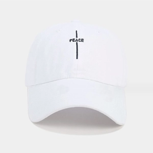 Détail de la broderie PEACE et croix noire sur une casquette en toile de coton blanc