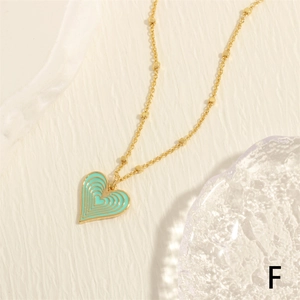 Macro detail of golden heart pendant with mint green enamel on a textured surface