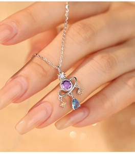 Macro detail of planet pendant with purple stone and colorful charms on silver chain