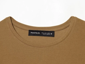 Detailed close-up of knitted neckline with lace-up detail and brand label on brown tee