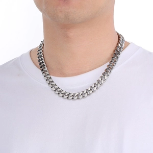 Close-up of polished silver stainless steel Cuban chain necklace on a male model's neck