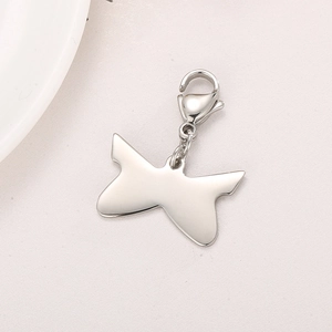 Polished silver butterfly pendant charm with secure lobster clasp on textured surface